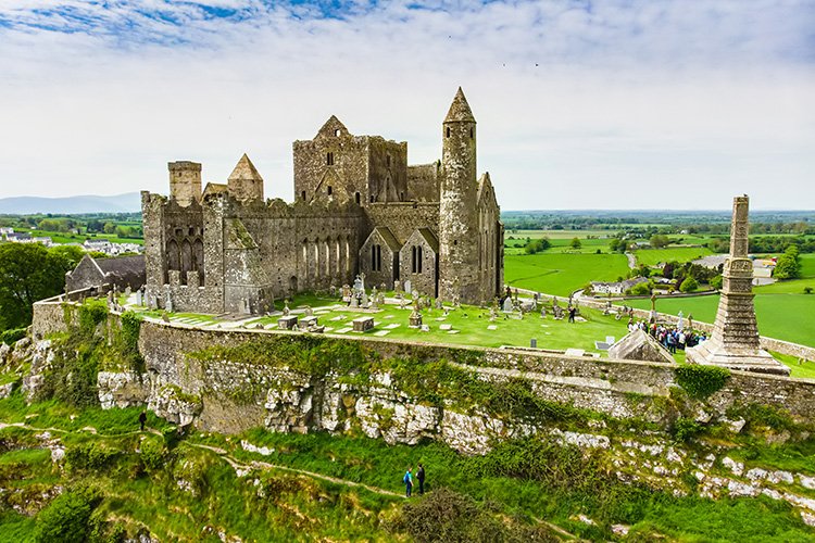 The Rock of Cashel seen from the road, with a wooden fence and grass in the foreground