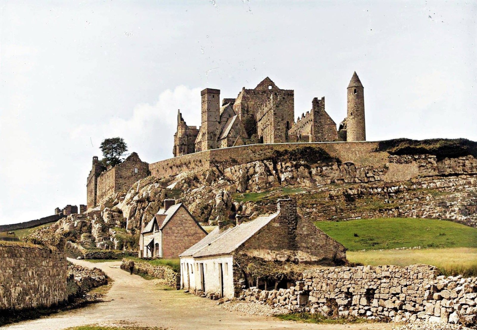 The Rock of Cashel behind a thatched cottage and a dry-stone wall