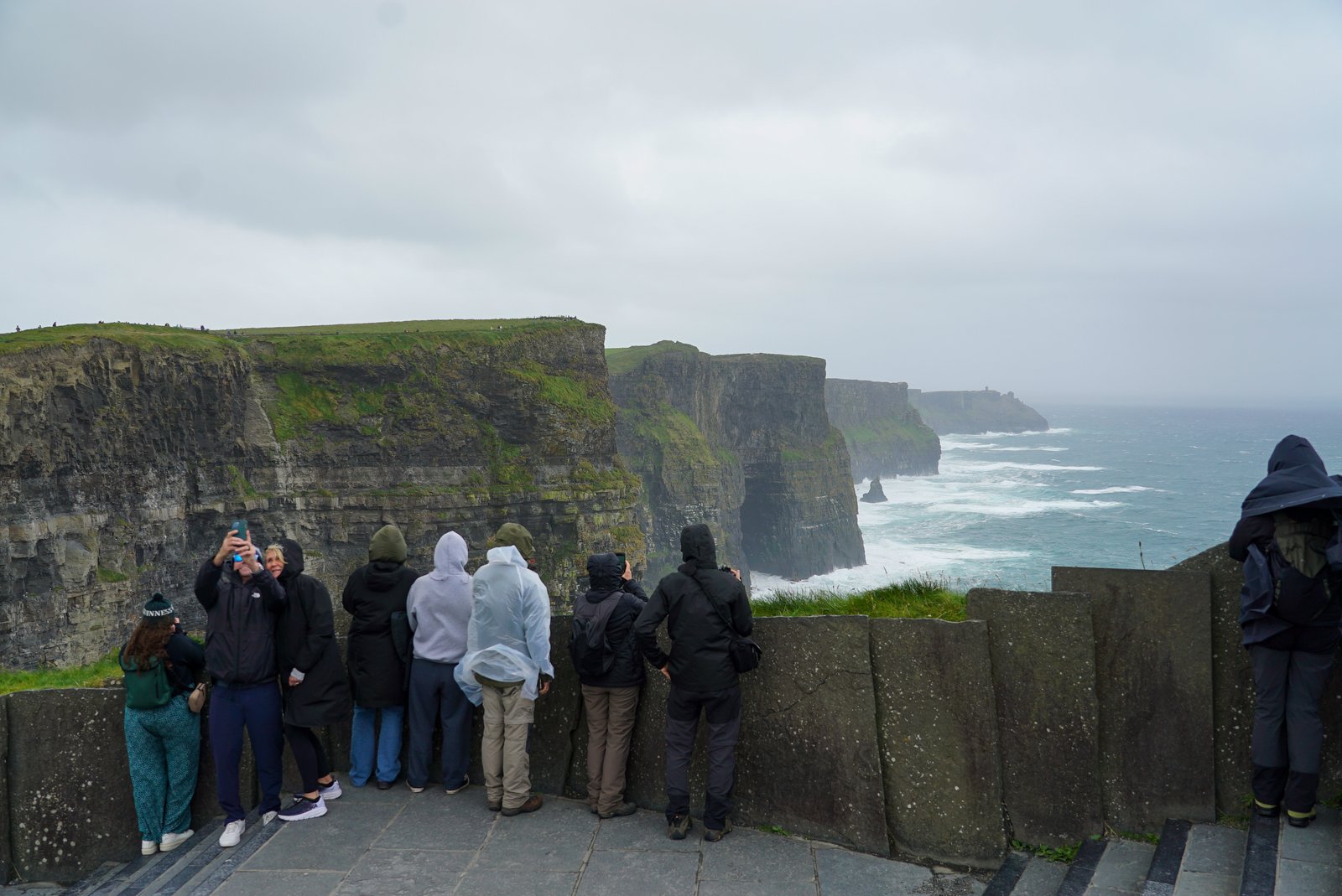 Visitors at a viewing platform looking along a line of sea cliffs on a grey day